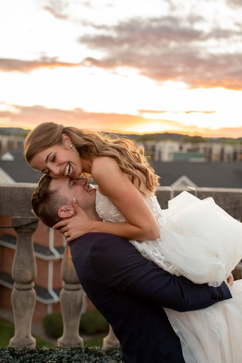 Groom holding bride while they rest their faces against each other