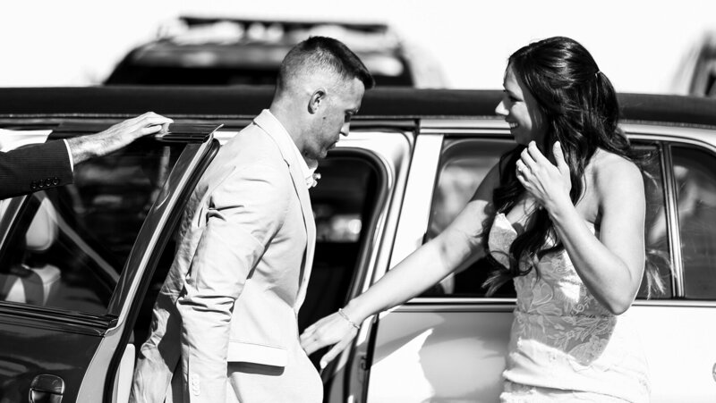 Bride pauses outside a car to take groom's hand
