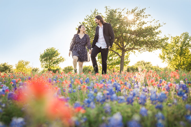 couple walking through a field of bluebonnets