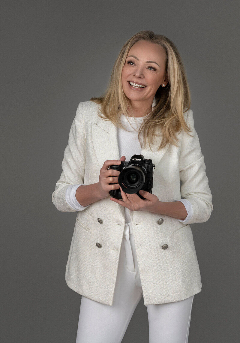 Black and white portrait of a smiling photographer with a camera.