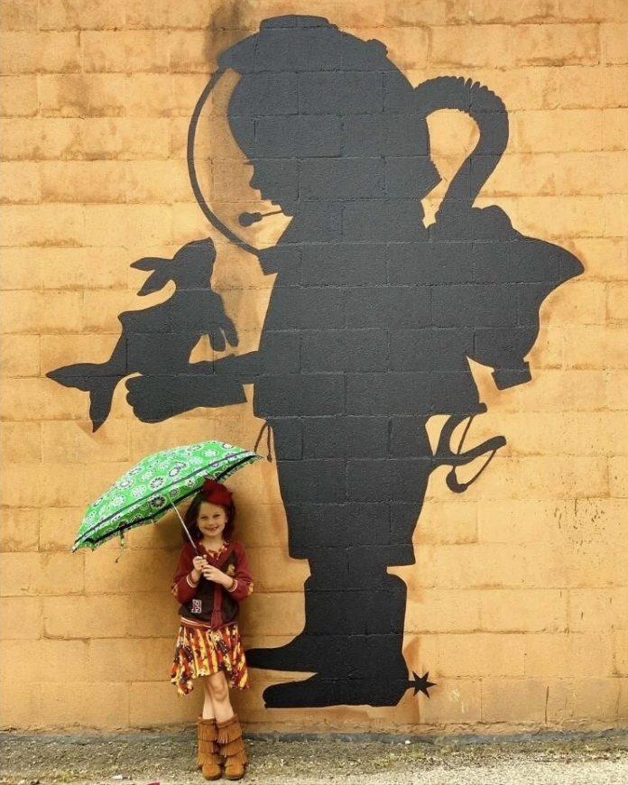 Girl with umbrella by mural