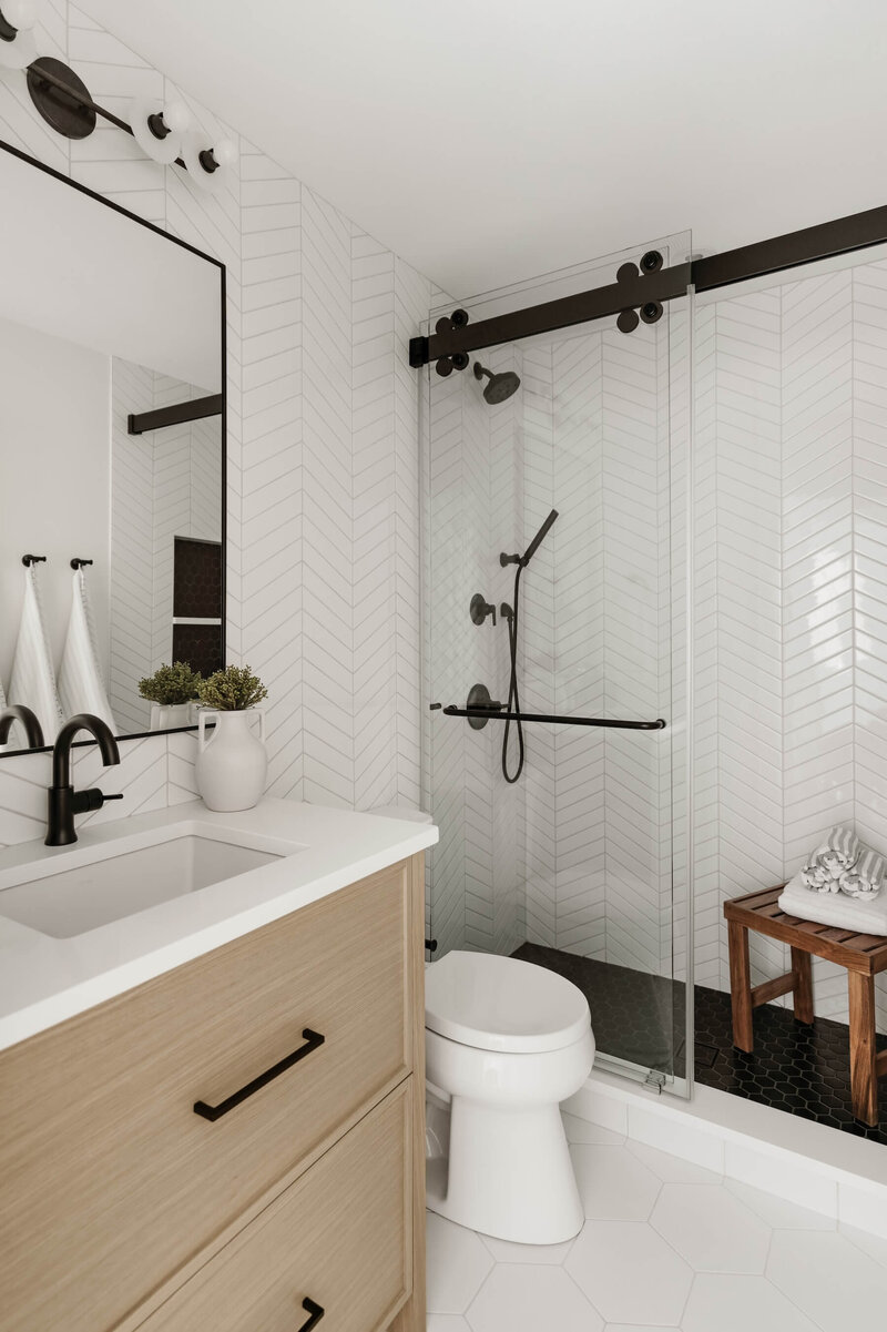 Guest bathroom with chevron subway tile and white oak vanity with black accents. 