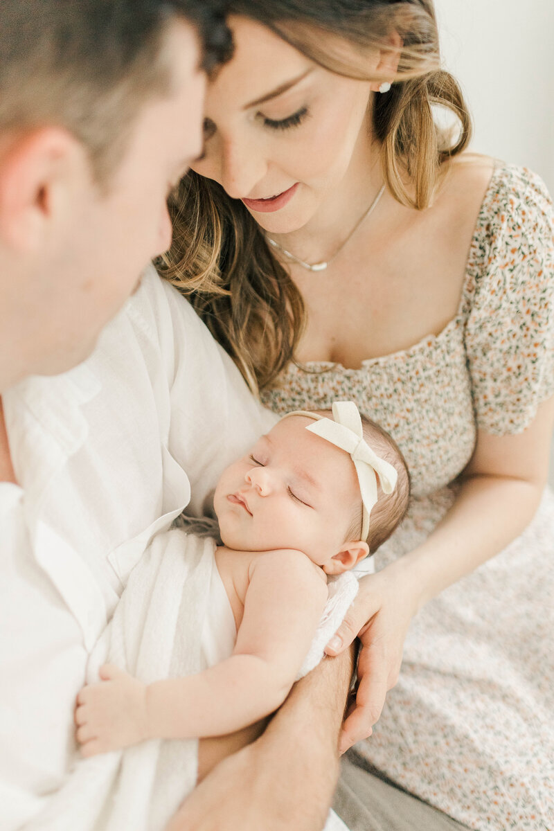 Close-up of a little girl in a straw hat sitting on her mother’s lap while delicately holding white flowers during a Kansas City mommy-and-me session.