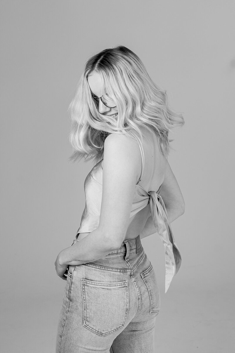 a black and white photo of a teen girl flipping her hair and looking behind her shoulder