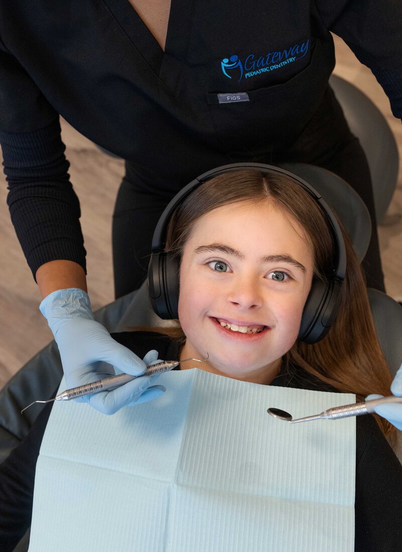 Pediatric dentist performing a restorative treatment on a child's tooth.