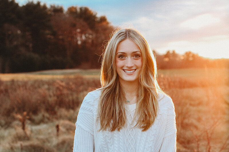 Young woman smiling for camera during portrait photoshoot.