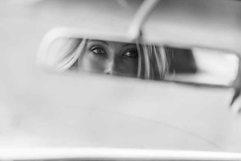 Tara looking in the rearview mirror of a car