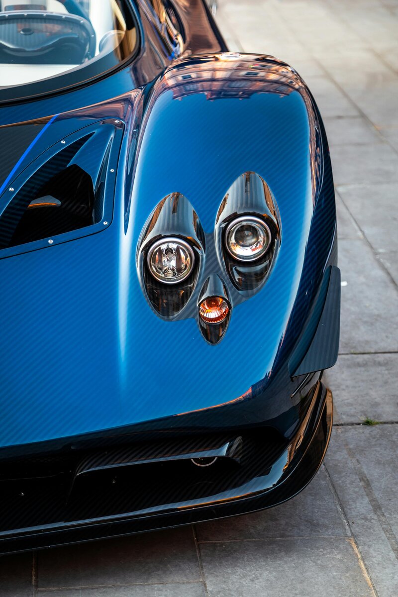 Close-up of the distinctive quad headlights and blue carbon fiber bodywork of a Pagani Zonda, likely receiving expert detailing services at Superstar Auto Spa in Queens, New York. This image highlights the unique design elements of this exotic supercar and the meticulous care provided by our auto spa