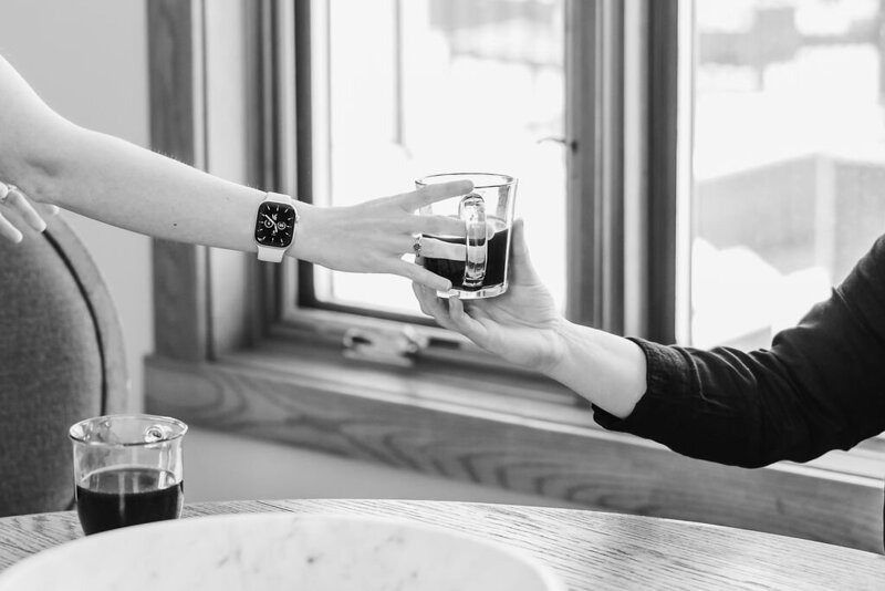 Black and white photo of someone handing a coffee mug to another person