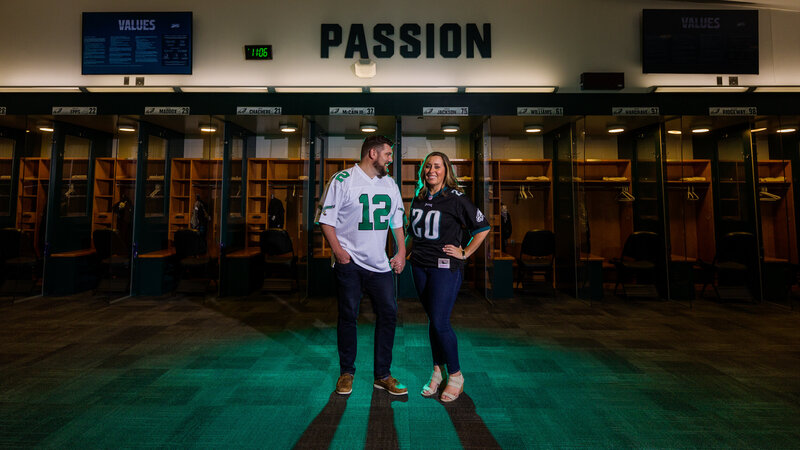 Engaged couple standing closely together in the Eagles Locker Room, blending their love story with their football passion.