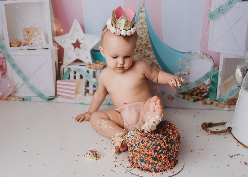 A baby putting her foot in a cake.