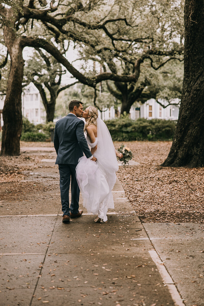 Bride and groom holding hands and kissing after their wedding in Pensacola, FL