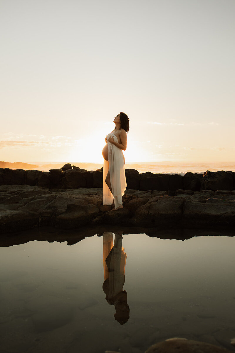 woman pregnant in a white button down on the beach