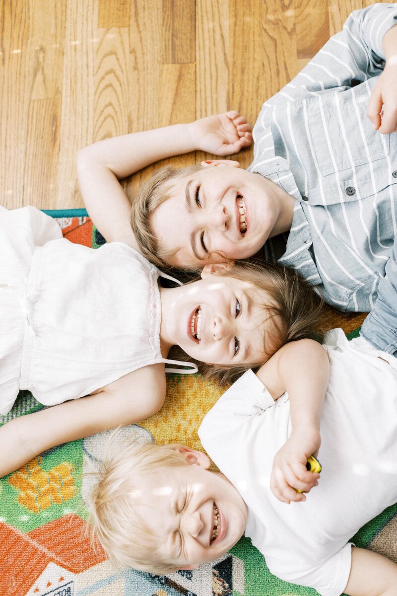 siblings laying on the floor laughing during peoria illinois in home family photos 