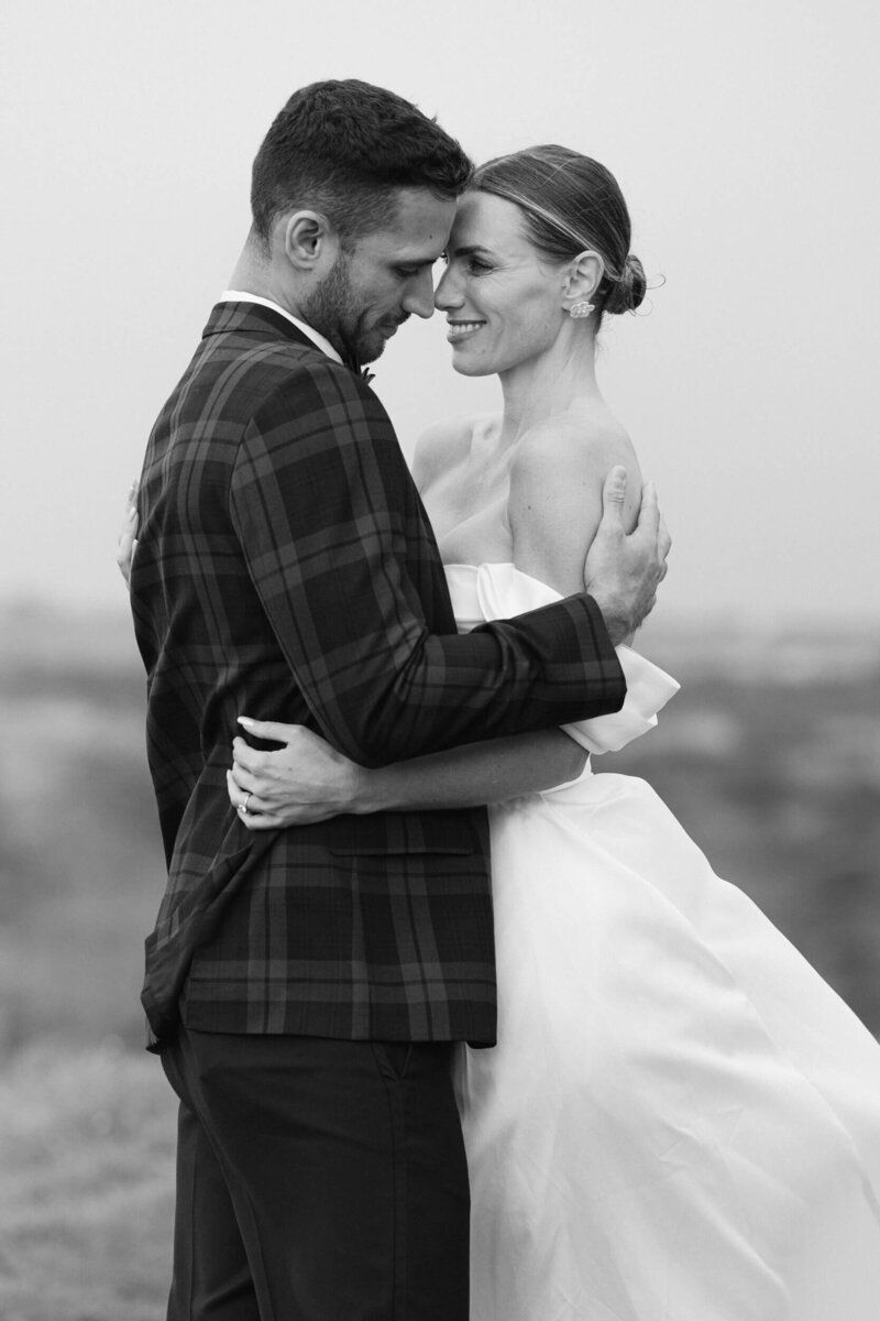 black and white photo of a couple during their elopement of them smiling and emracing each other at the top of the cliffs of moher