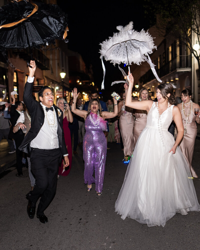 Bride and groom with umbrellas during wedding second line parade through the French Quarter