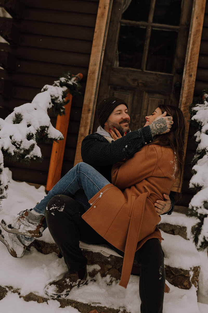 Colorado couple embraces in the snow outside a cabin