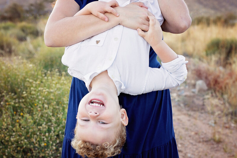 A mom holds her son upside down while he laughs