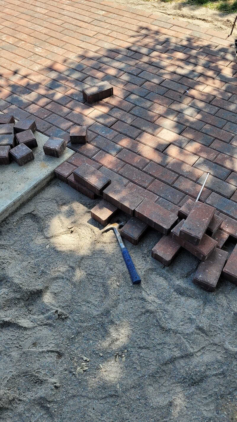 Bricks and a hammer place patio pavers into order outside in Missoula, Montana.