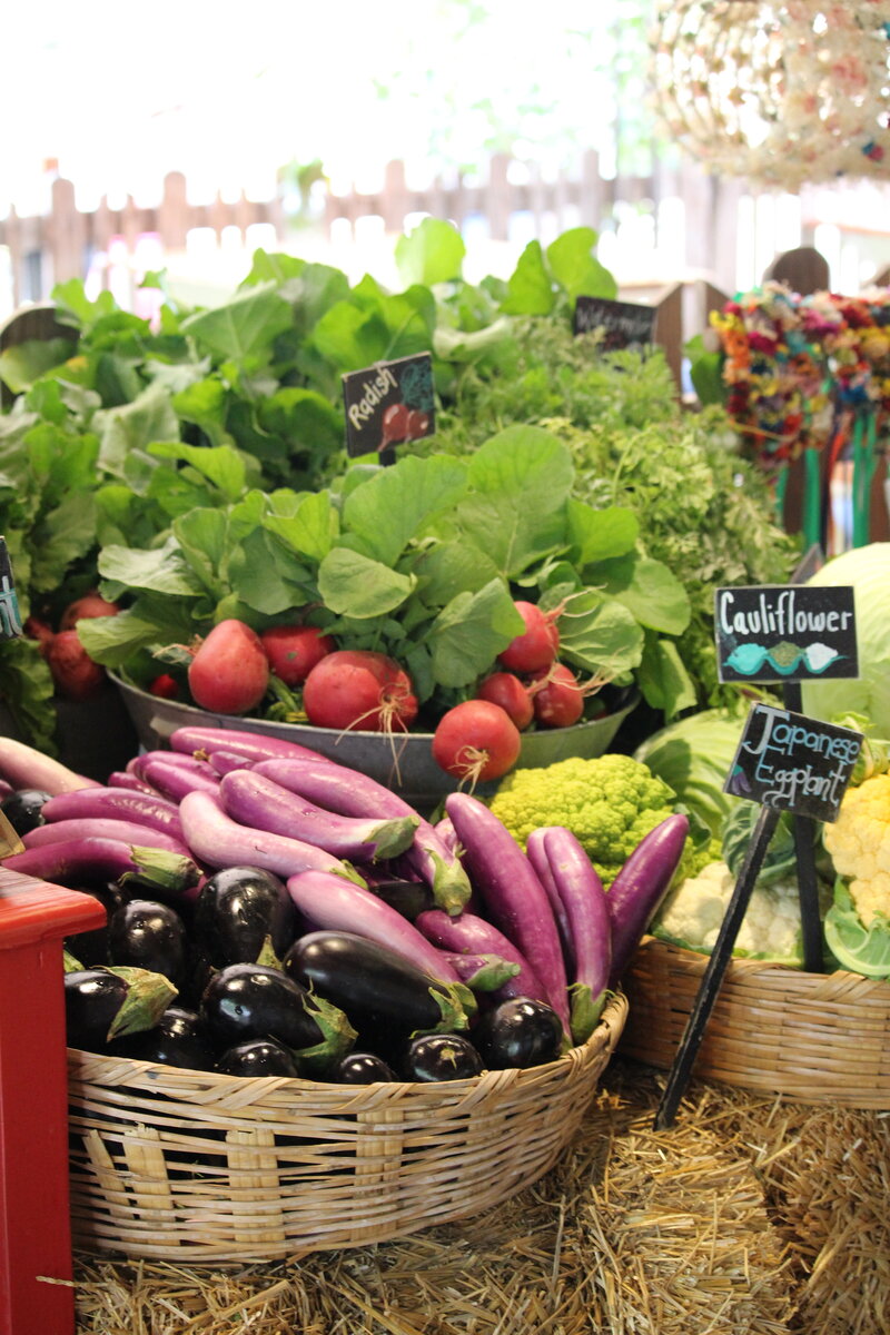 Image of a farmer's market table with fresh vegetables including eggplant, cauliflower, and radishes.