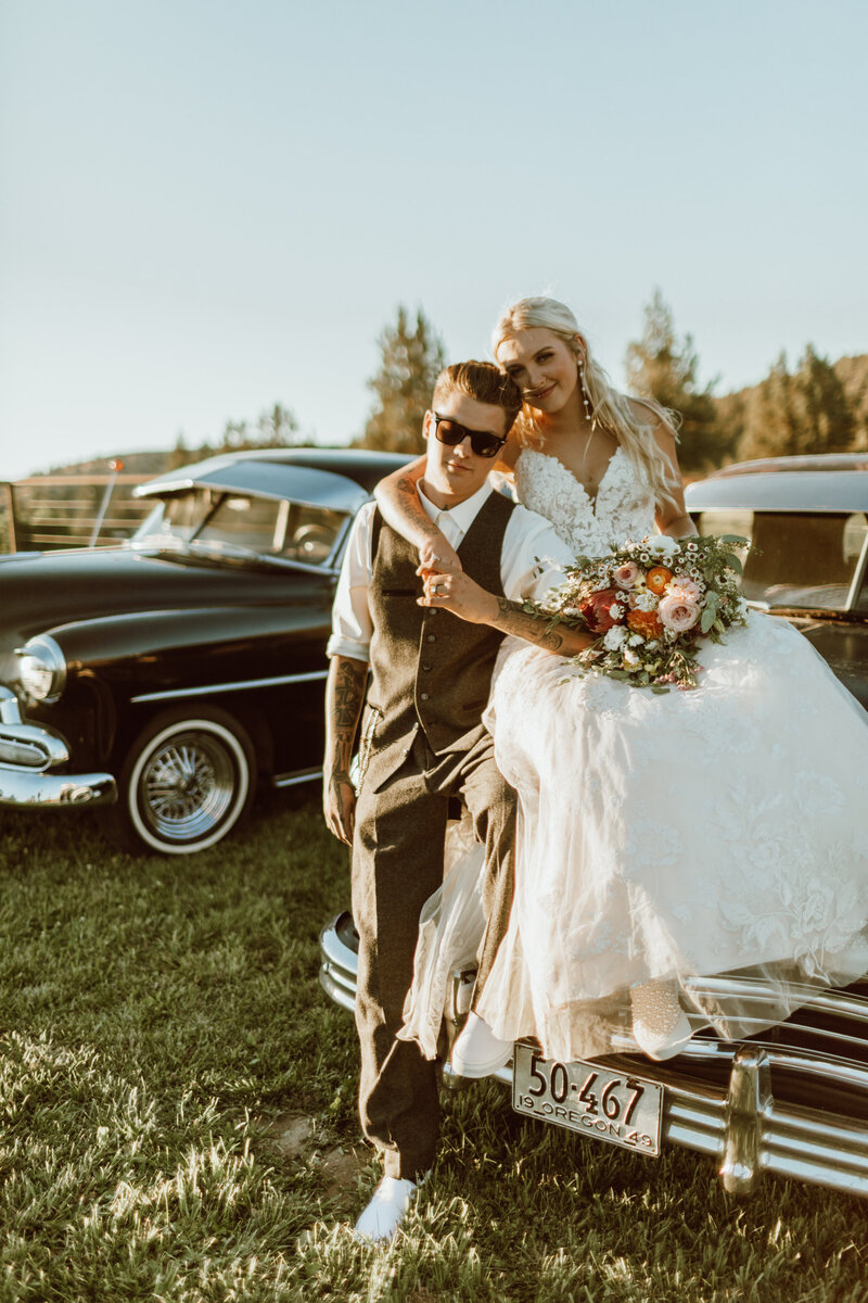 bride and groom posing on a classic car