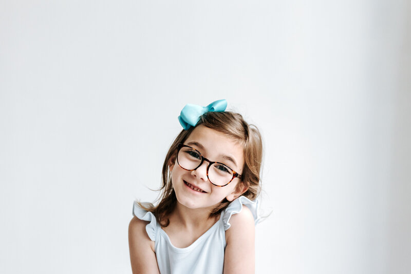 female photographer wearing pink pants and white top sitting next to a disco ball