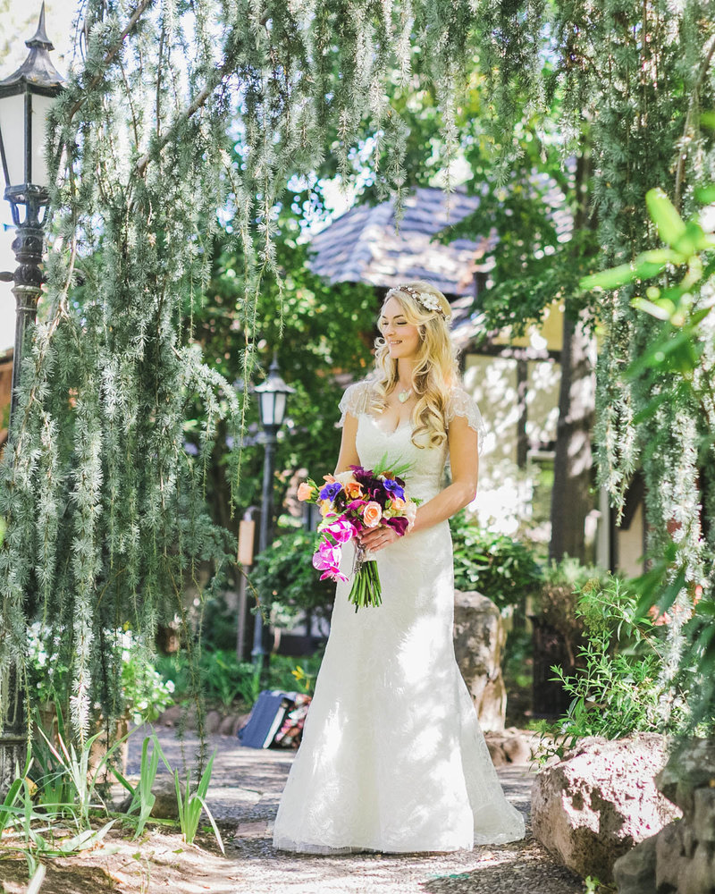 Candid of Bride standing on a path holding her bouquet and smiling