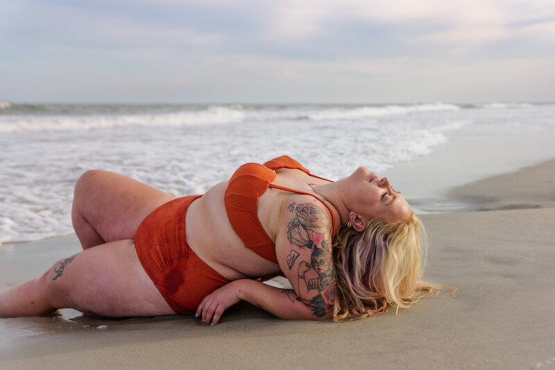Plus size model posed flatteringly in the ocean, while waves roll over her at sunset in Myrtle Beach, SC.