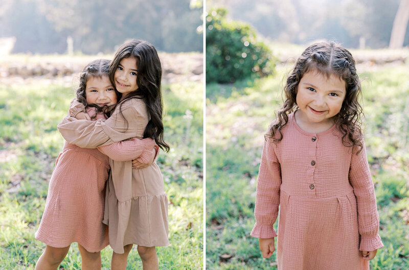 Two young sisters wearing pink dresses hug each other during their session with child portrait photographer Daniel Rose