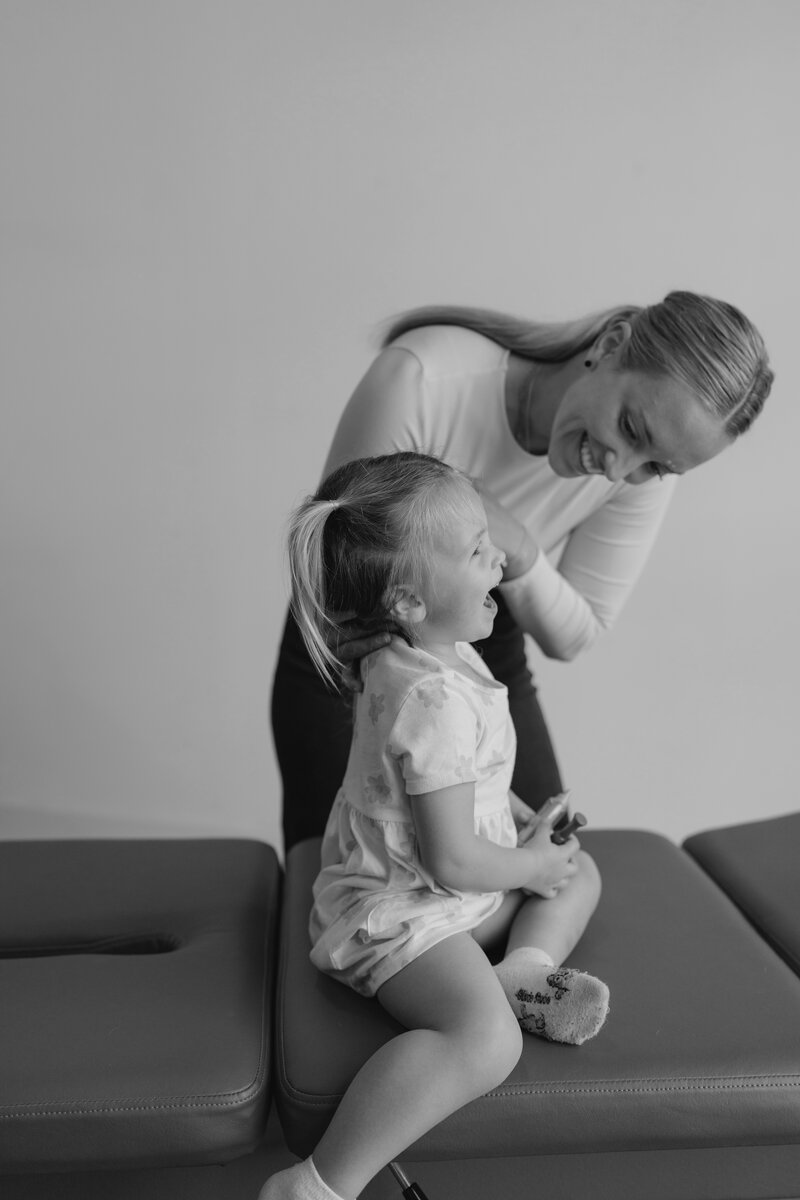 woman adjusting young girl on chiropractic table