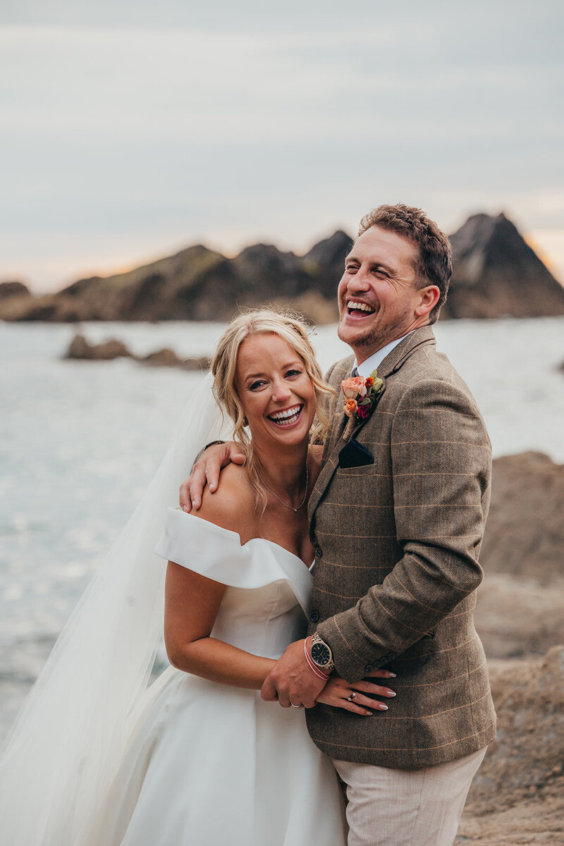 bride and groom laughing on the beach