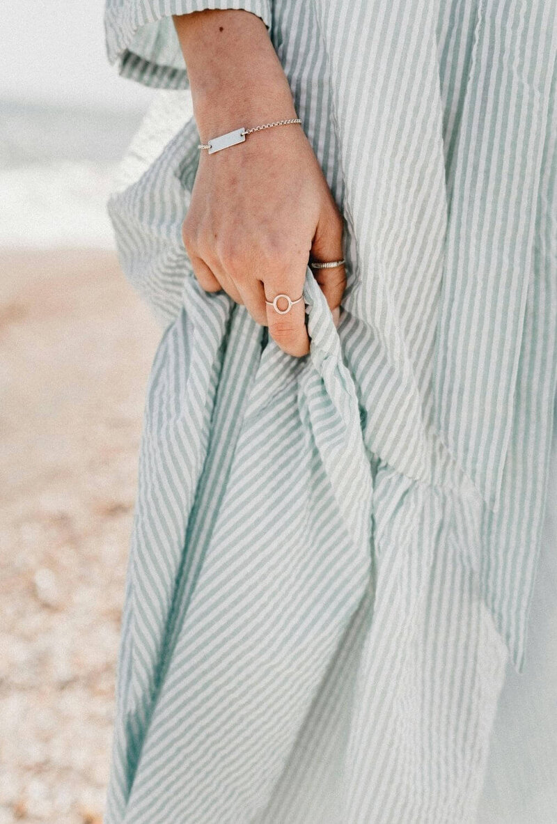 Women's hand holding folds of striped beach dress