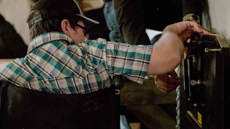 The back of a  man in a wheel chair seeking healing through equine therapy at Spirit's Respite Ranch near Edmonton, Alberta
