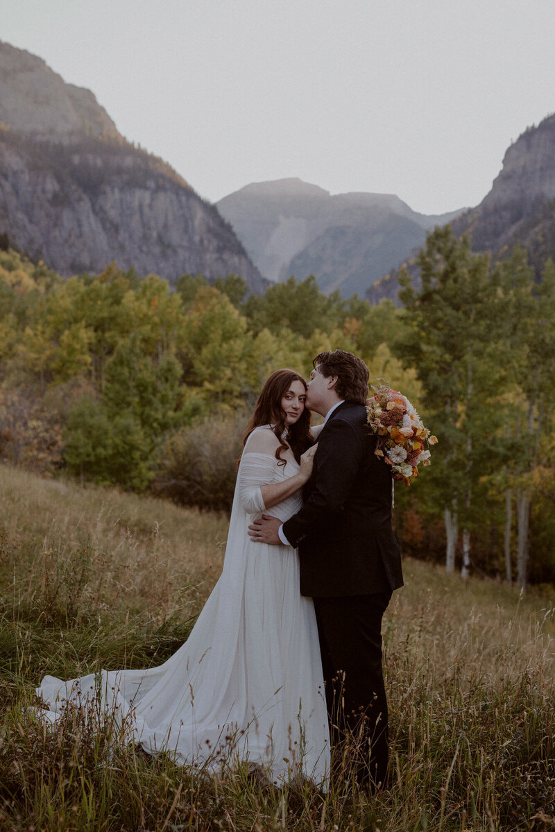 Bride and groom hold each other in the mountains