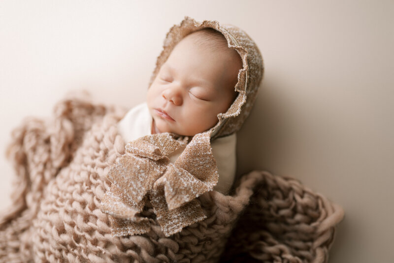 Newborn wrapped in brown blanket with brown bonnet
