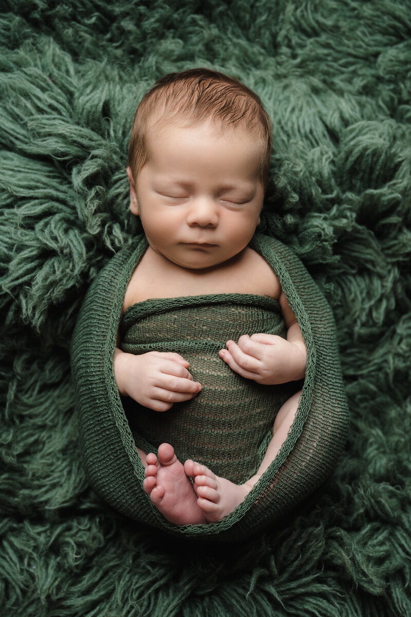 newborn boy wrapped in green