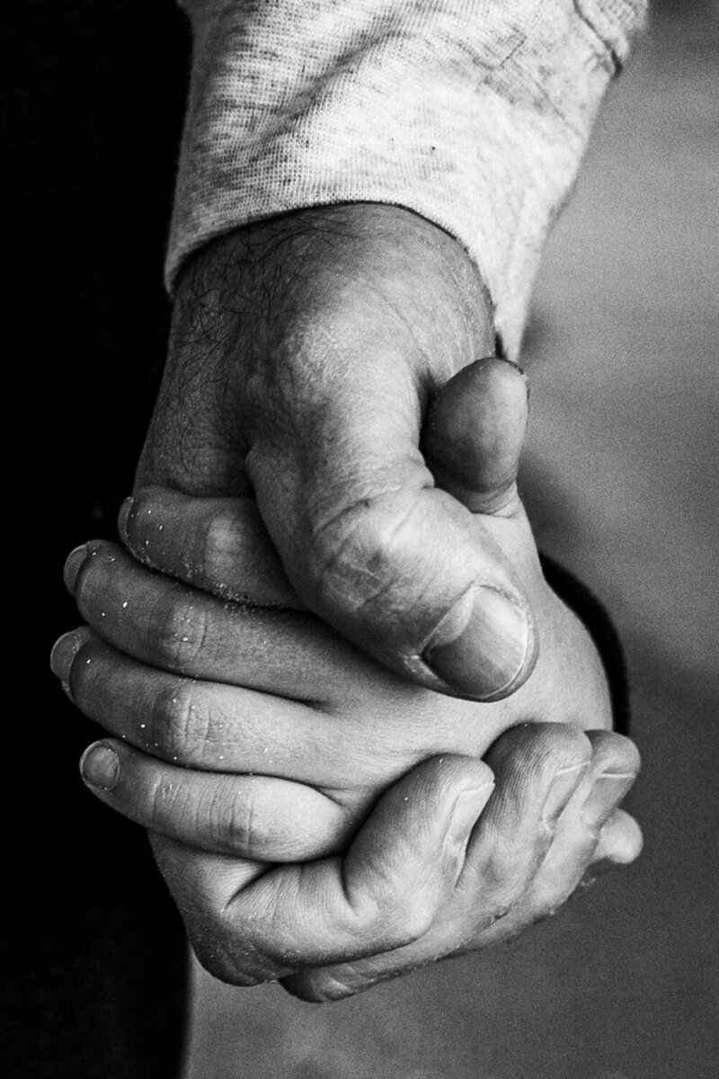 Black and white close up of dad and child holding hands