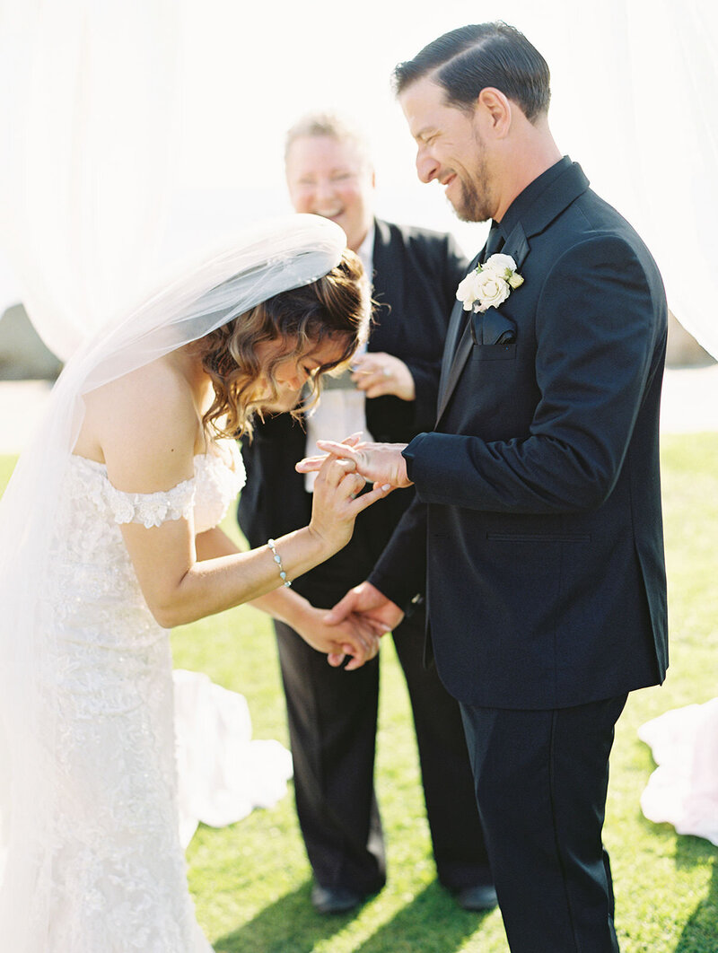 bride, groom, and officiant break down in laughter while putting on the rings during a wedding ceremony at the wedding bowl in la jolla