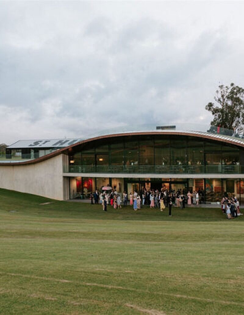 A modern event space with large glass windows built into the side of a grass hill.