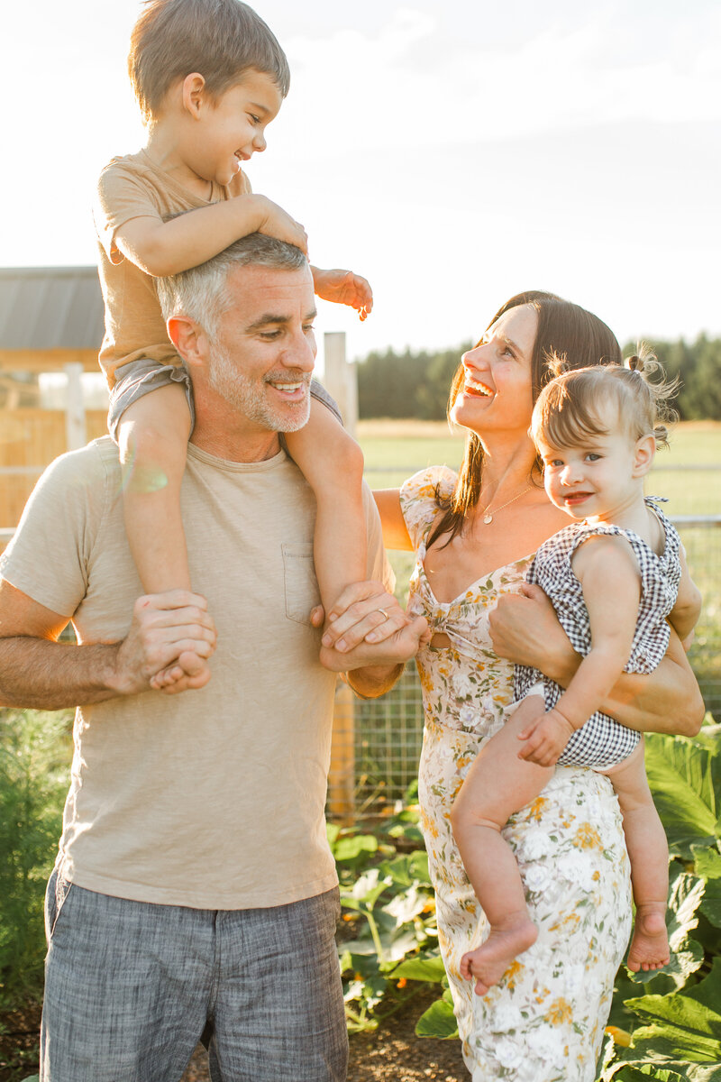 Father carrying the child on his shoulder while mother holding the other child