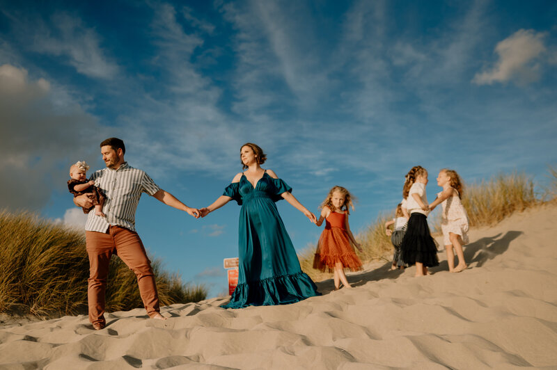 Family standing in line on sand with blue sky.