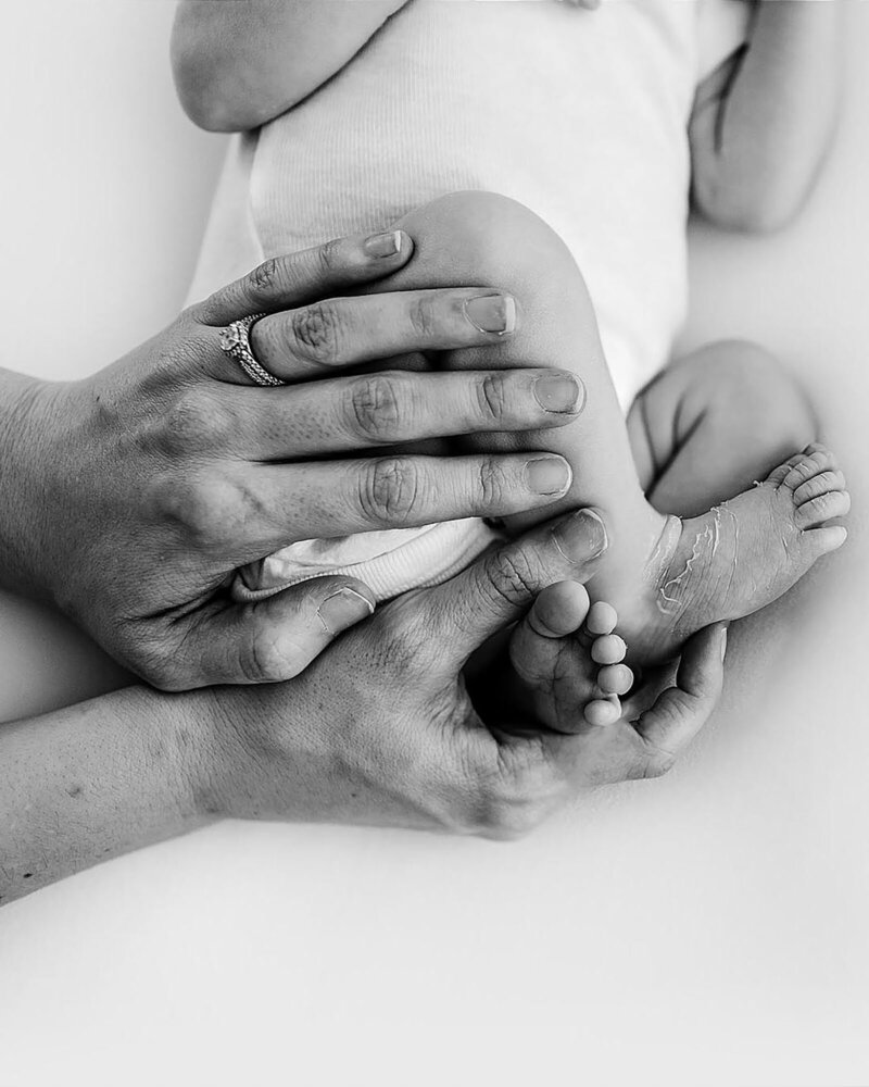 black and white close up of mothers hands during Navarre Newborn Photography session