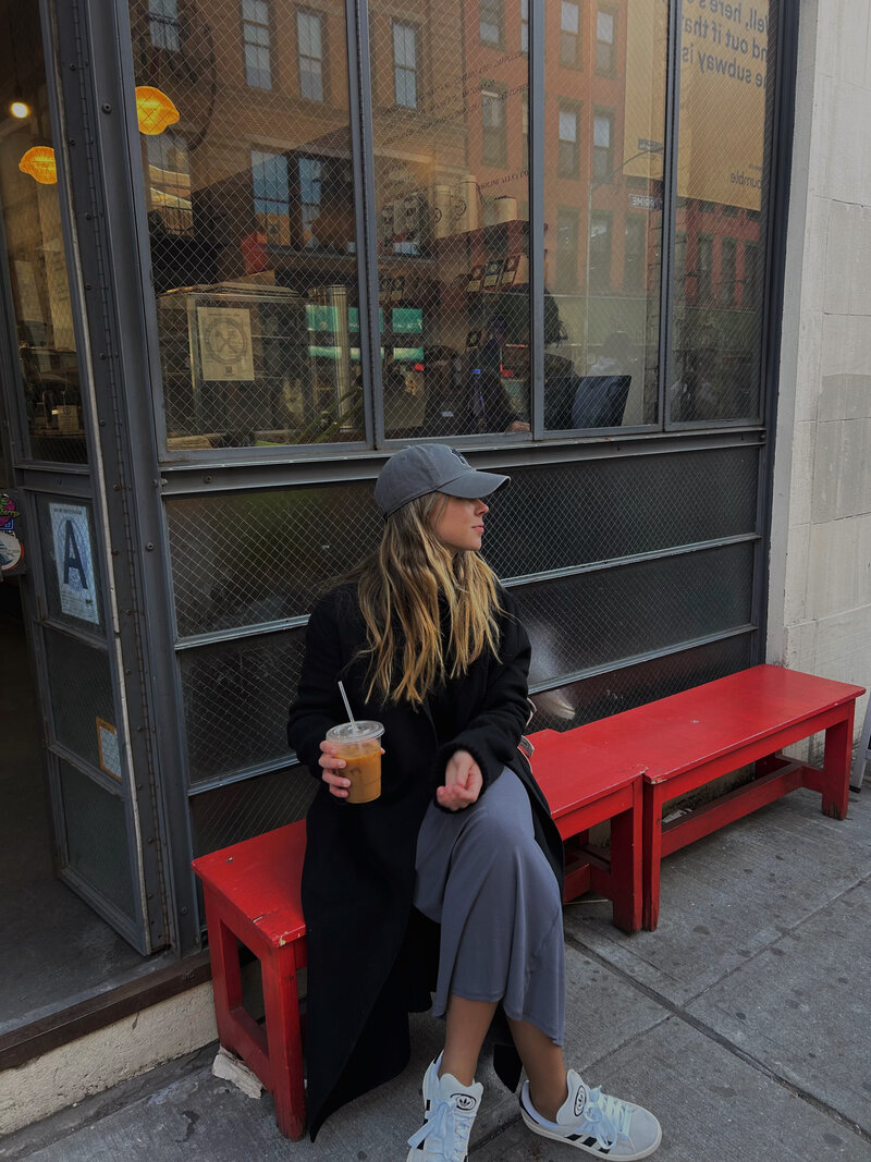 a woman sitting on a park bench drinking a coffee after an EMDR intensive