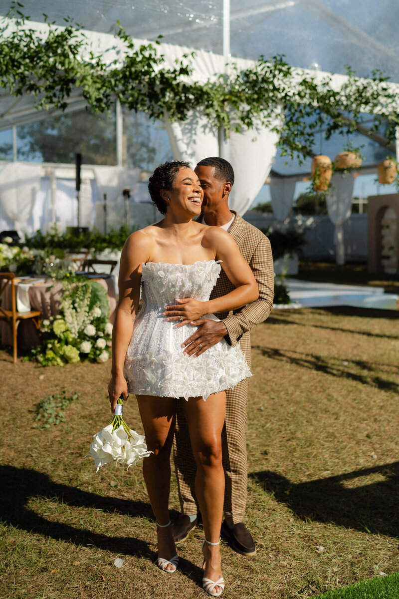 bride leans into her husband as he kisses her cheek in the sunlight