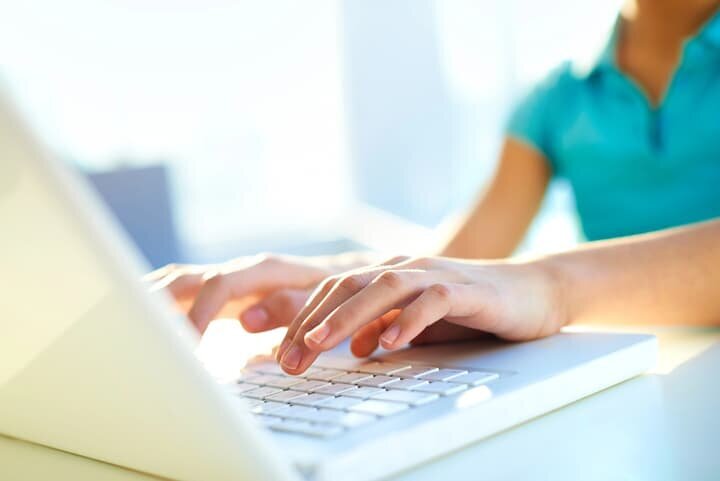 Writer's hands typing on laptop keyboard, utilizing manuscript editing services