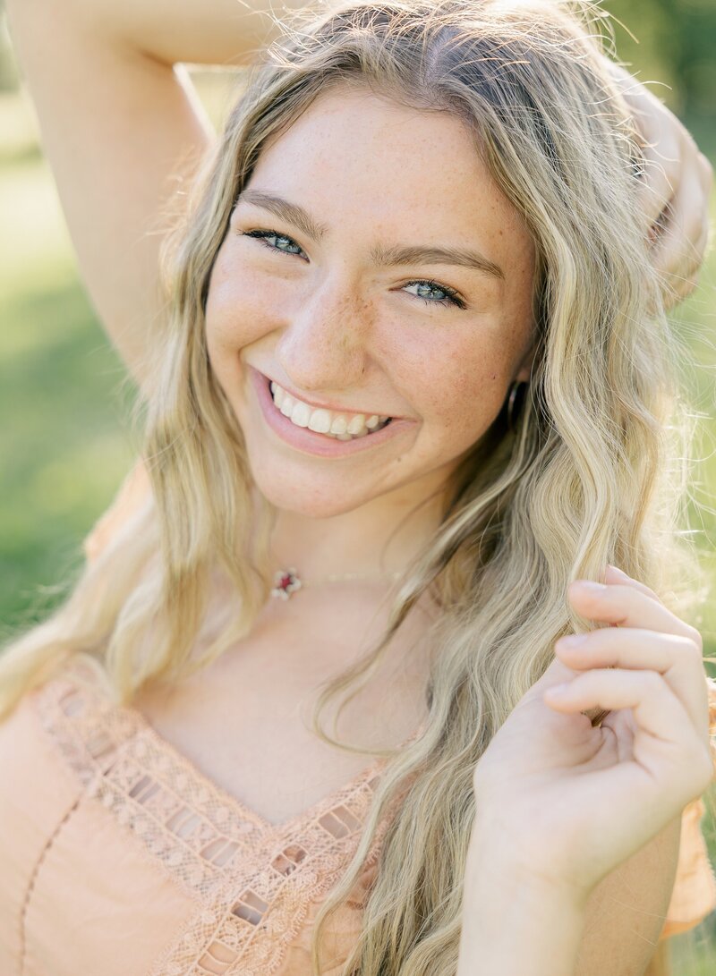 senior girl smiles at camera with her hands in her hair, Indianapolis senior photos