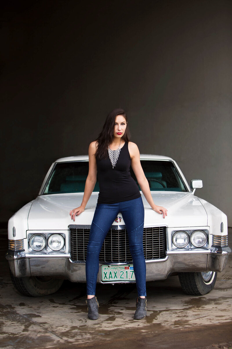 model leaning on  hood of vintage cadillac