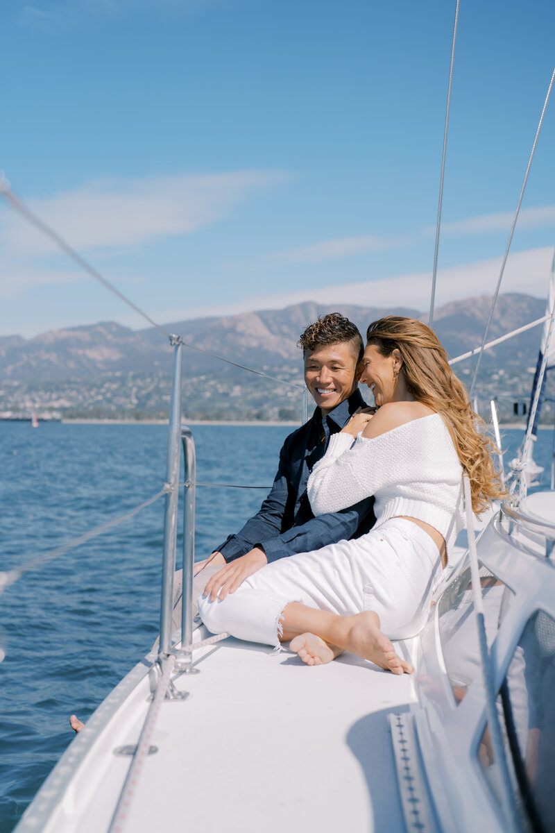 Couple smiling and sitting on sailboat in Santa Barbara Harbor