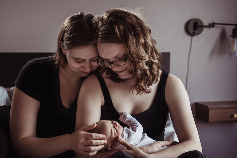 two lesbian mothers hold their newborn baby