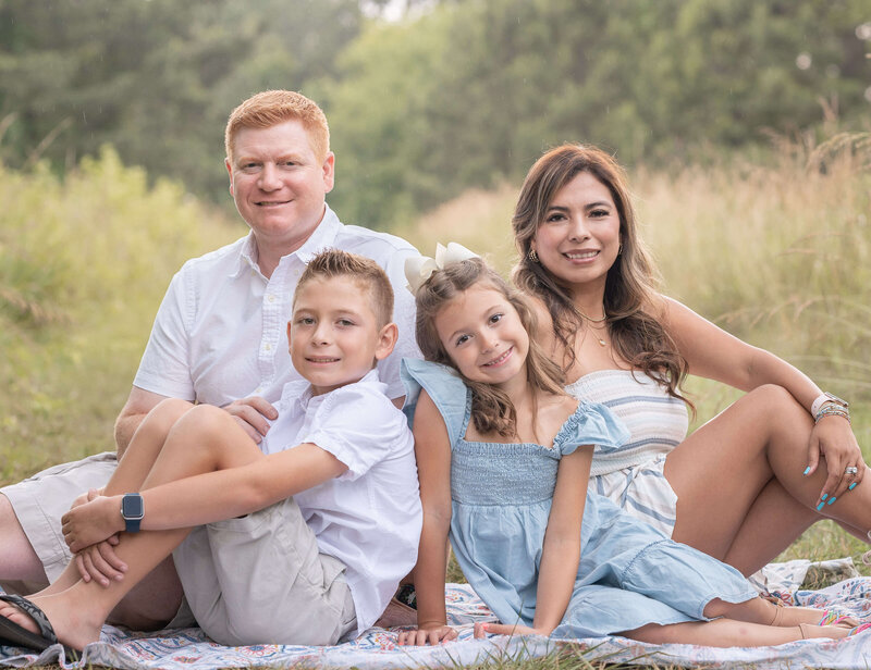 family of four sitting down on the floor and looking at the camera during photos taken at Green meadows preserve in Marietta, Georgia